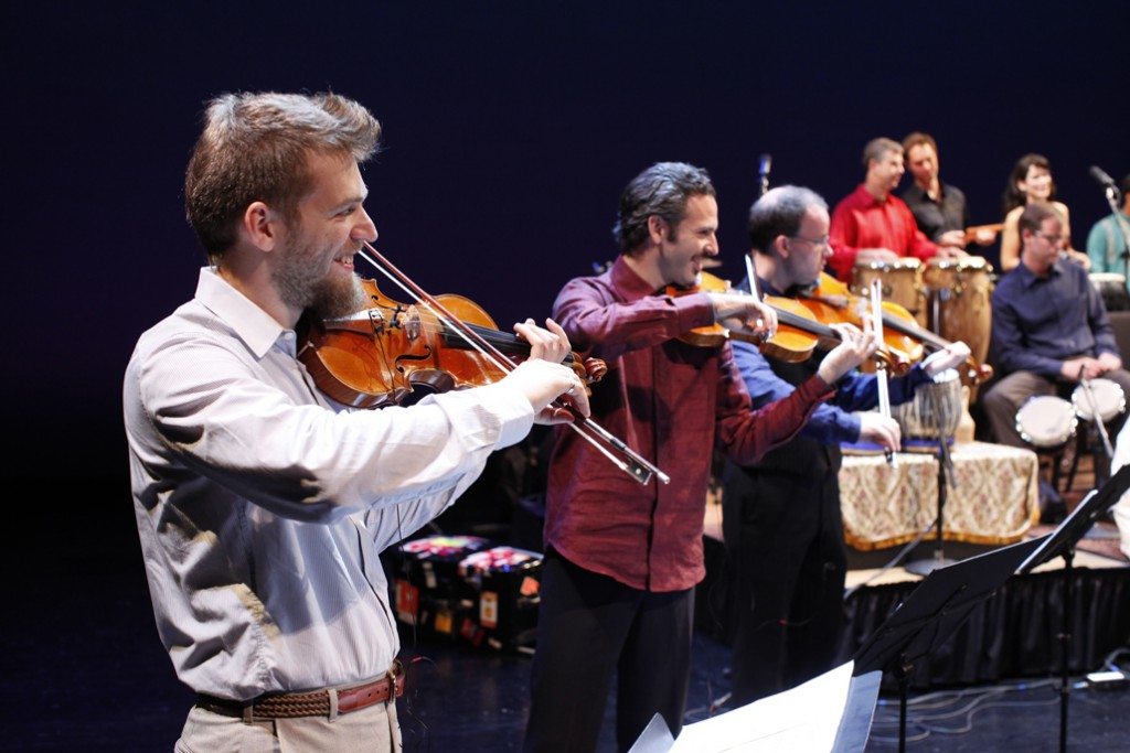 Johnny Gandelsman (violin), Colin Jacobsen (violin), and Nicholas Cords (viola) performing with fellow Silk Road Ensemble musicians © Todd Rosenberg Photography